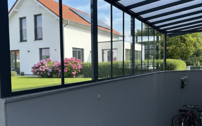 Carport mit schwarzer Seitenwand und M&uuml;lltonnen