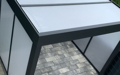 Carport mit schwarzer Seitenwand und M&uuml;lltonnen