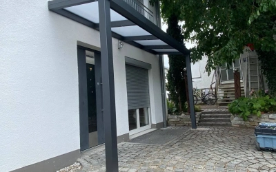 Eingangsschutz mit Glasdach und Windschutzwand
